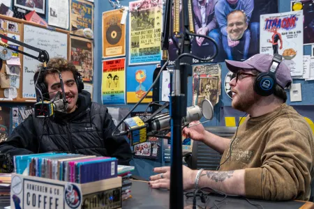 Students in front of microphones in a radio studio.