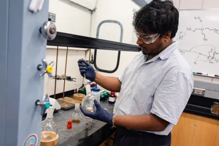 A college student wearing goggles in a chemistry lab.