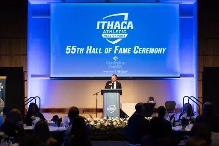 A man at a podium speaks at IC's 55th Athletics Hall of Fame Ceremony.