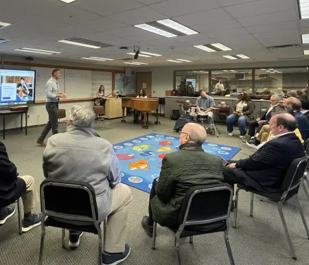 Man talks to people sitting in chairs in a circle.