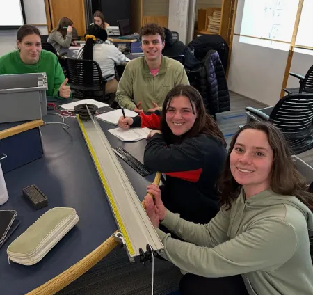 Students smiling with a standing wave experiment.