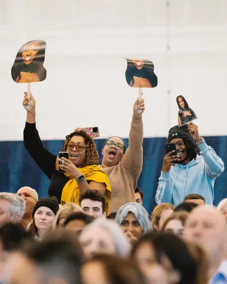 Friends and family hold up signs depicting a graduate's face at Commencement.