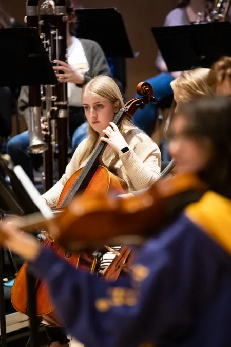 A college student plays the cello in an orchestra.