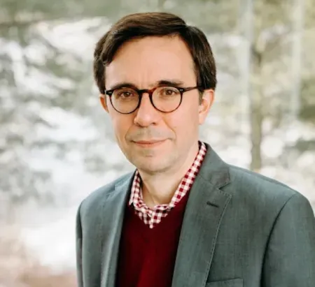 man wearing glasses with sweater and suit coat