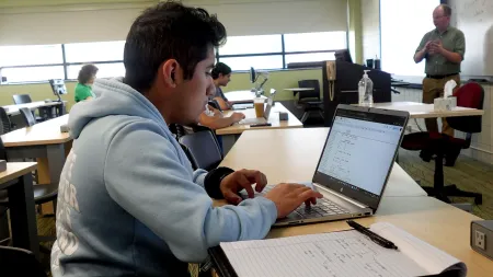 Students engaged in a computers and info tech class with faculty