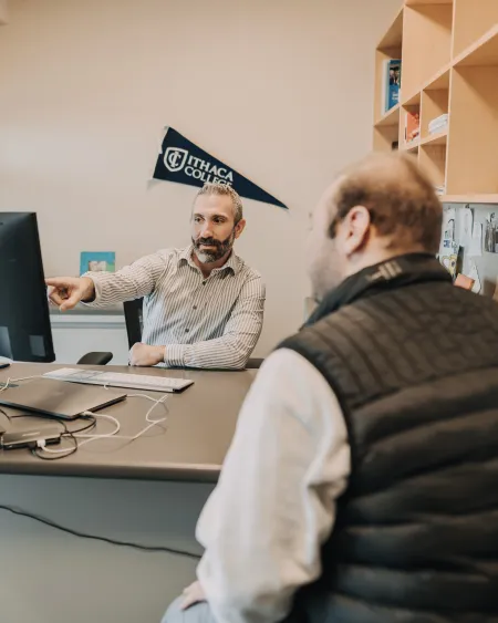 A student and a career counselor sit at a desk.