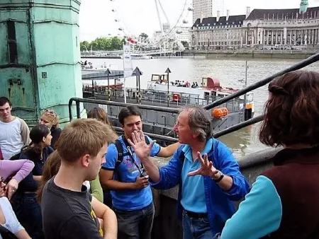 Bill Sheasgreen standing by the Thames River in London, speaking to a group of students