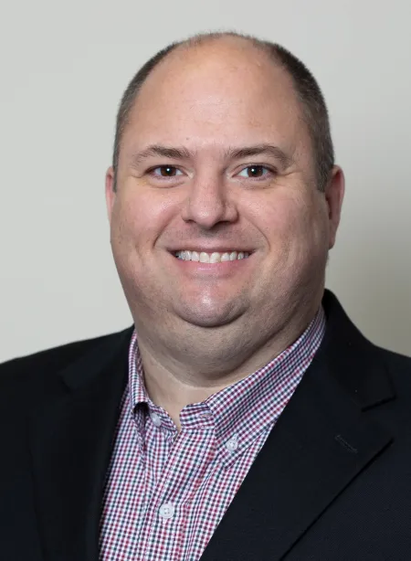 Man wearing a checkered shirt and dark coat.