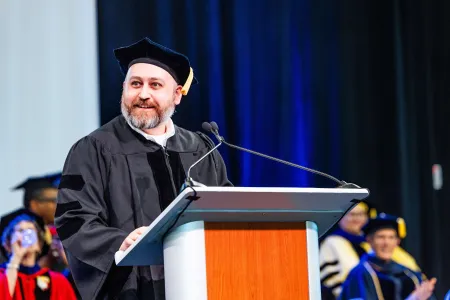 A man with cap and gown at a podium.
