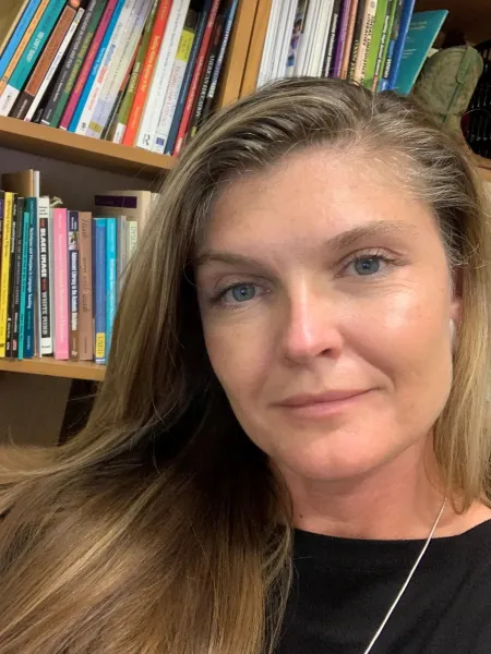 Woman in front of a bookshelf.