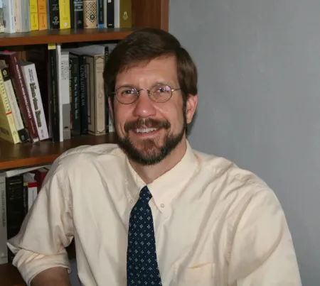 Bearded man wearing a white shirt and a tie.