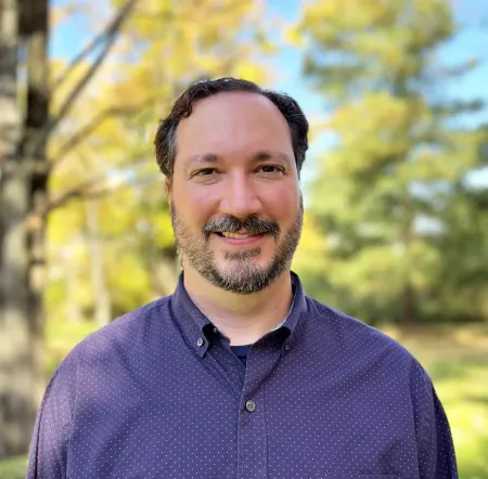 Bearded man wearing a purple shirt.