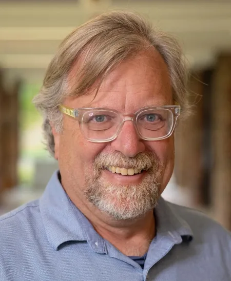 Bearded man wearing glasses and a blue shirt.