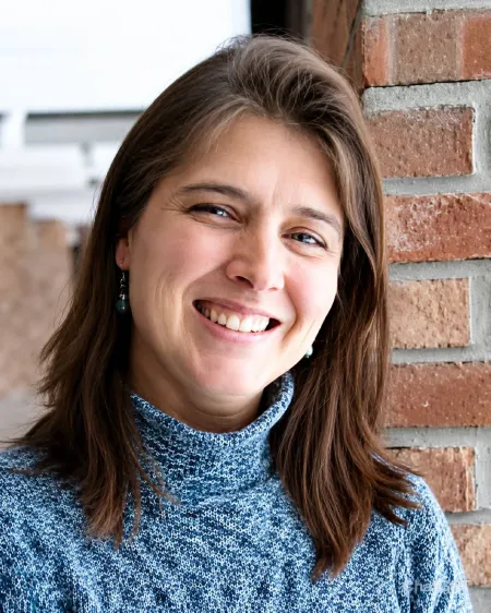 Dark haired woman wearing a blue turtleneck