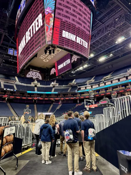 Students standing in a basketball arena.