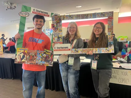 Three students holding creative signs.