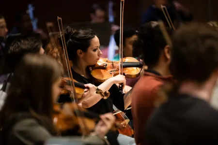 College violinists perform in an orchestra.