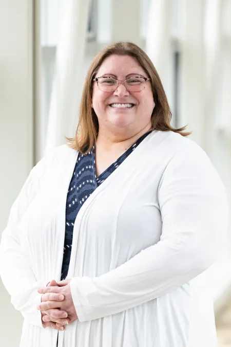 Image of Laura Davis. She is wearing a white sweater and blue patterned shirt. She is facing the camera and smiling.