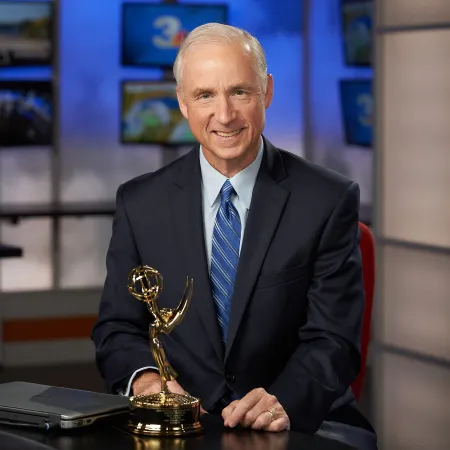 A man in a suit with an Emmy Award. 