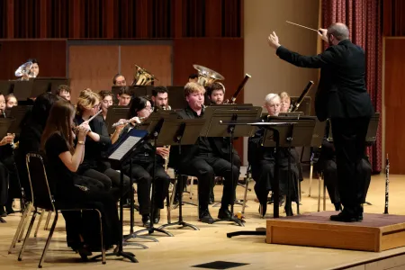A conductor leads a college wind ensemble.