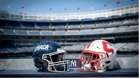 Image of Ithaca (left) and Cortland (right) football helmets on table with Yankee Stadium grandstand in backdrop.