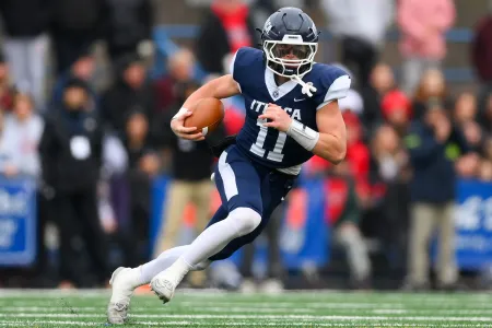 A college football player wearing #11 runs with the ball.