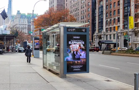 A bus shelter on Broadway at West 77th Street displays an American Museum of Natural History ad for "The Secret World of Elephants."