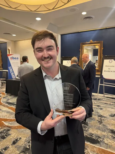 Peter Champelli smiles and holds a glass SABEW Best in Business award at an awards event.
