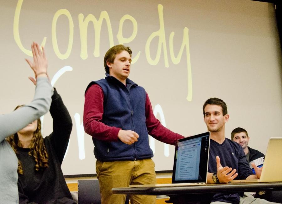 Five individuals around open laptops conducting a writing workshop. 