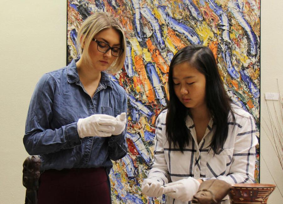 Teacher and student examining pottery