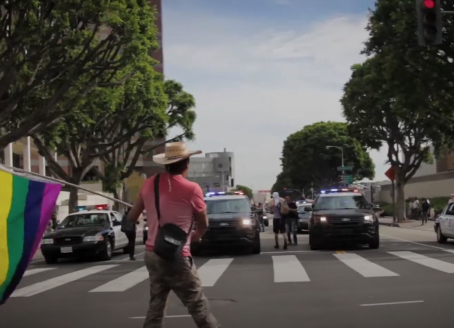 Image of man with flag in front of police cars