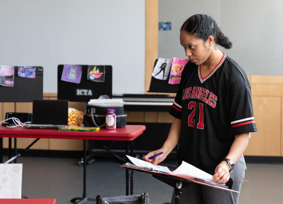 A Theatre Studies student stands at a music stand with a script open.