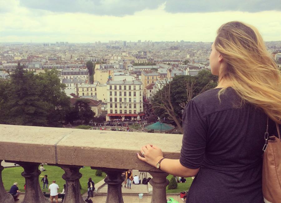 A long-haired woman gazing out over the city of Paris