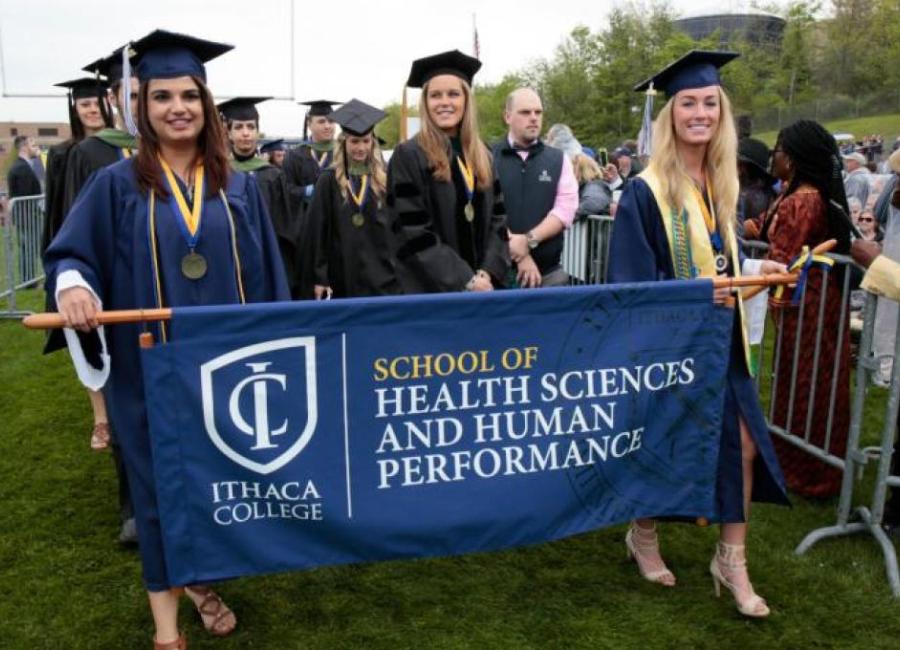 Students graduating holding an HSHP banner.