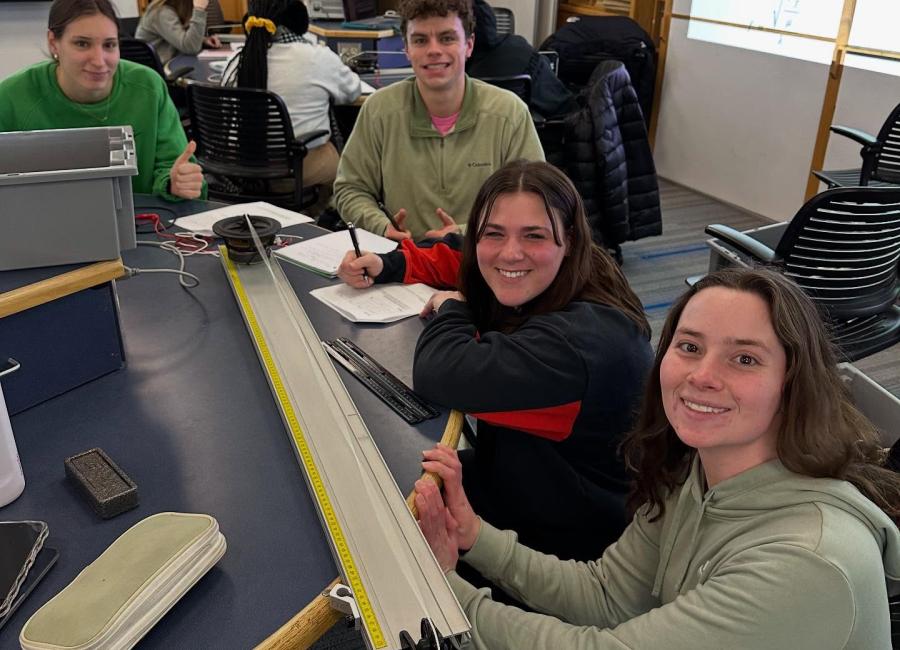 Students explore standing waves using a stretched string and a speaker.