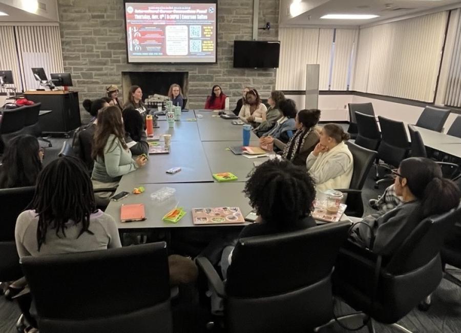a group of female students sits around a large table having a discussion