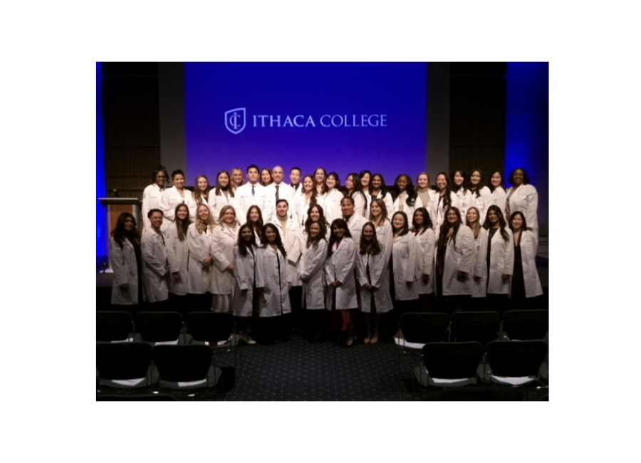 a group of students poses together wearing long white coats 