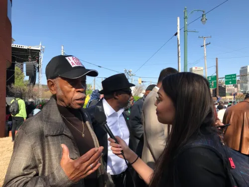 Student holds a microphone up to interview subject.