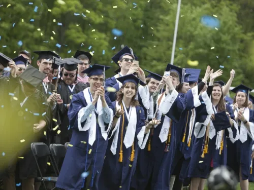 Graduates in robes watching confetti