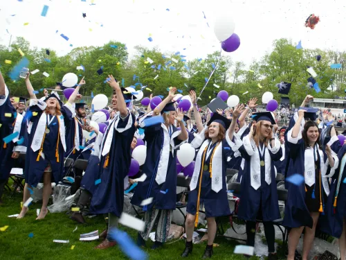 Graduates in caps and gowns celebrate with confetti