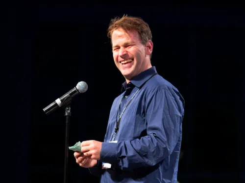 A man laughing in front of a microphone