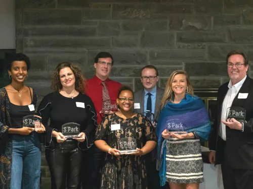 A group of men and women holding glass awards