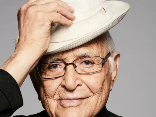 An older man with his hand on his hat