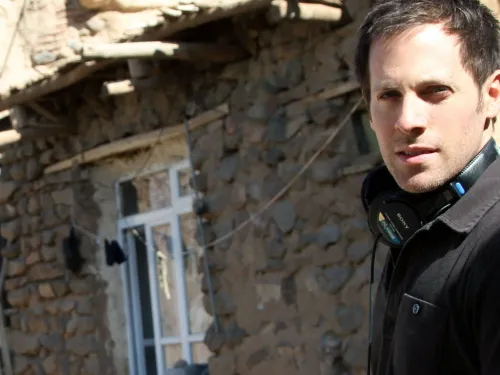 A man wearing headphones in front of stone buildings