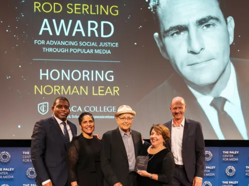 A group of men and women standing in front of a screen on stage