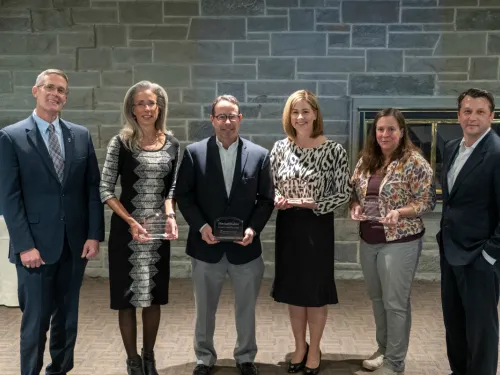 A group of men and women pose with awards