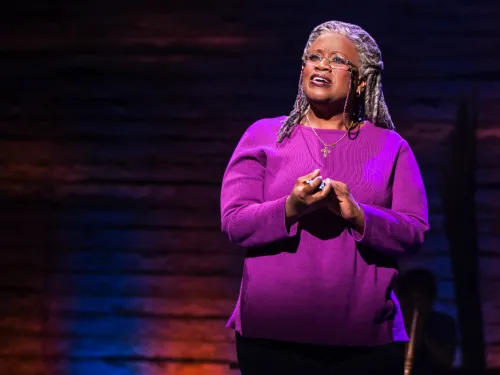 A black woman with long grey hair on stage