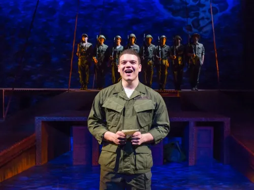A man in military fatigues sings on stage