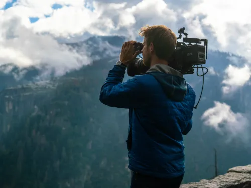 A man holds a video camera in the wilderness