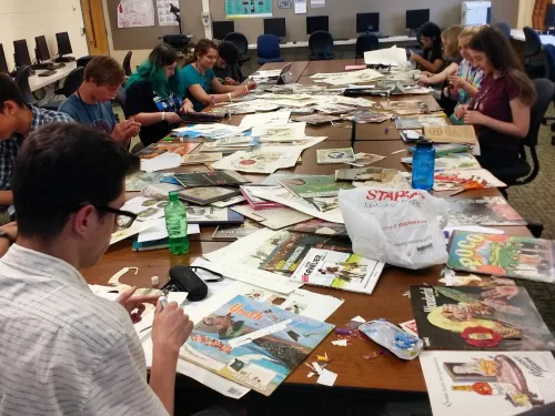 Students cutting magazines for a project in a classroom.